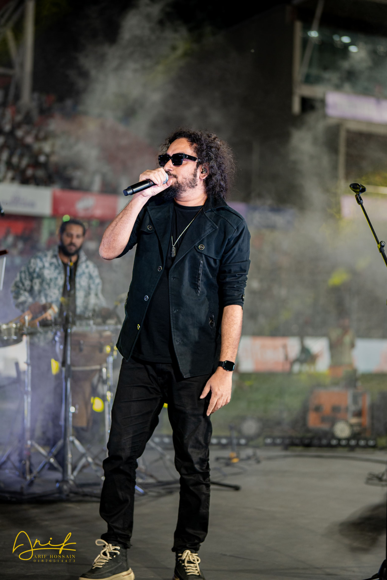 Muttaque Hasib singing into a handheld microphone on stage